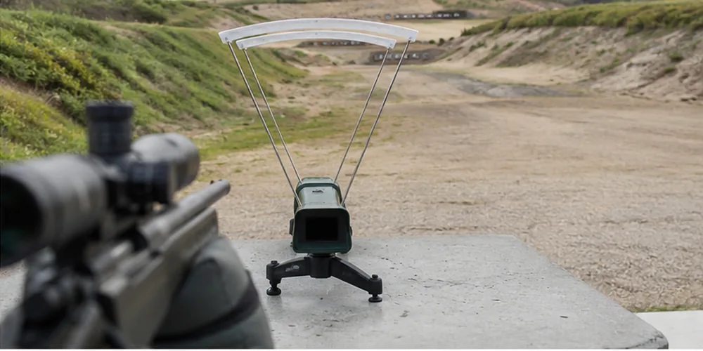 Chronograph set up downrange of a rifle on a bench